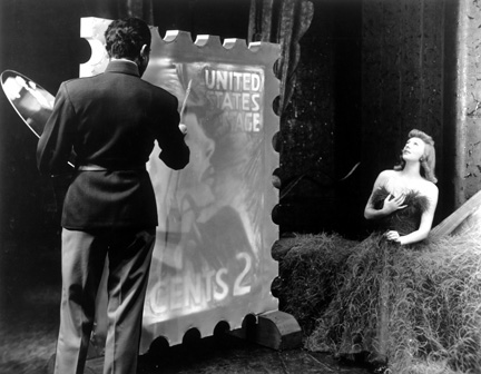 Gertrude Lawrence as Liza Elliott in the original Broadway production of LADY IN THE DARK, 1941. Liza Elliott’s portrait is painted for the 2-cent stamp during the Glamour Dream. Gertrude Lawrence as Liza Elliott in the original Broadway production of LADY IN THE DARK, 1941. Liza Elliott’s portrait is painted for the 2-cent stamp during the Glamour Dream.
